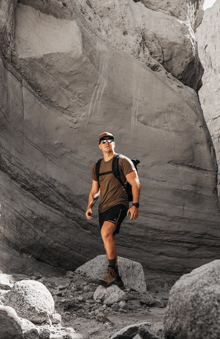 A confident man wearing a Bamboo Tank Top stands tall in a lush forest. The eco-friendly bamboo fabric provides comfort and breathability, allowing him to stay cool and stylish during his outdoor adventure